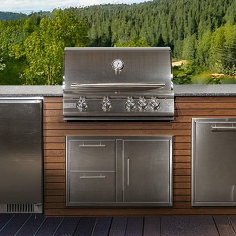 Outdoor kitchen island with a built-in stainless steel grill and black granite countertop overlooking a lake