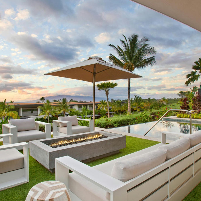 Luxury Airbnb outdoor space with modern fire pit, lounge seating, infinity pool, and tropical landscaping at sunset"