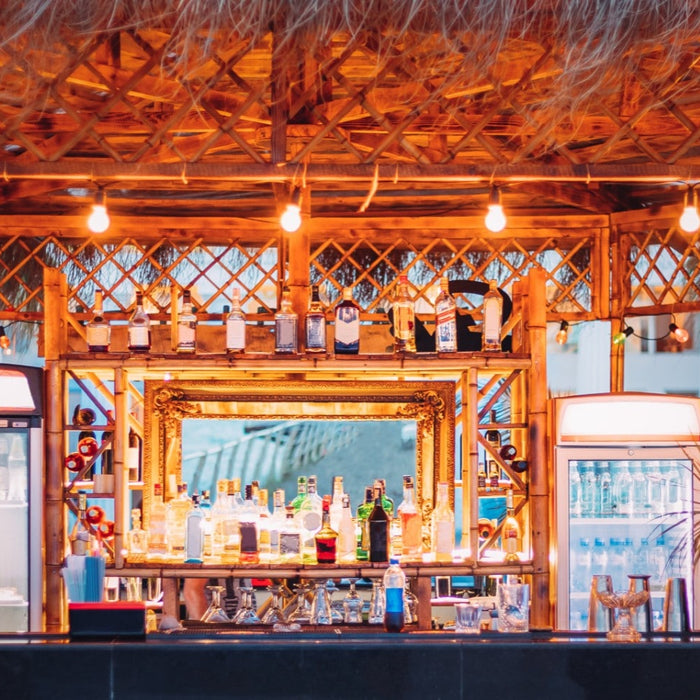 Tropical outdoor bar setup with warm string lights, bamboo accents, and a fully stocked backlit bar area at a vacation rental