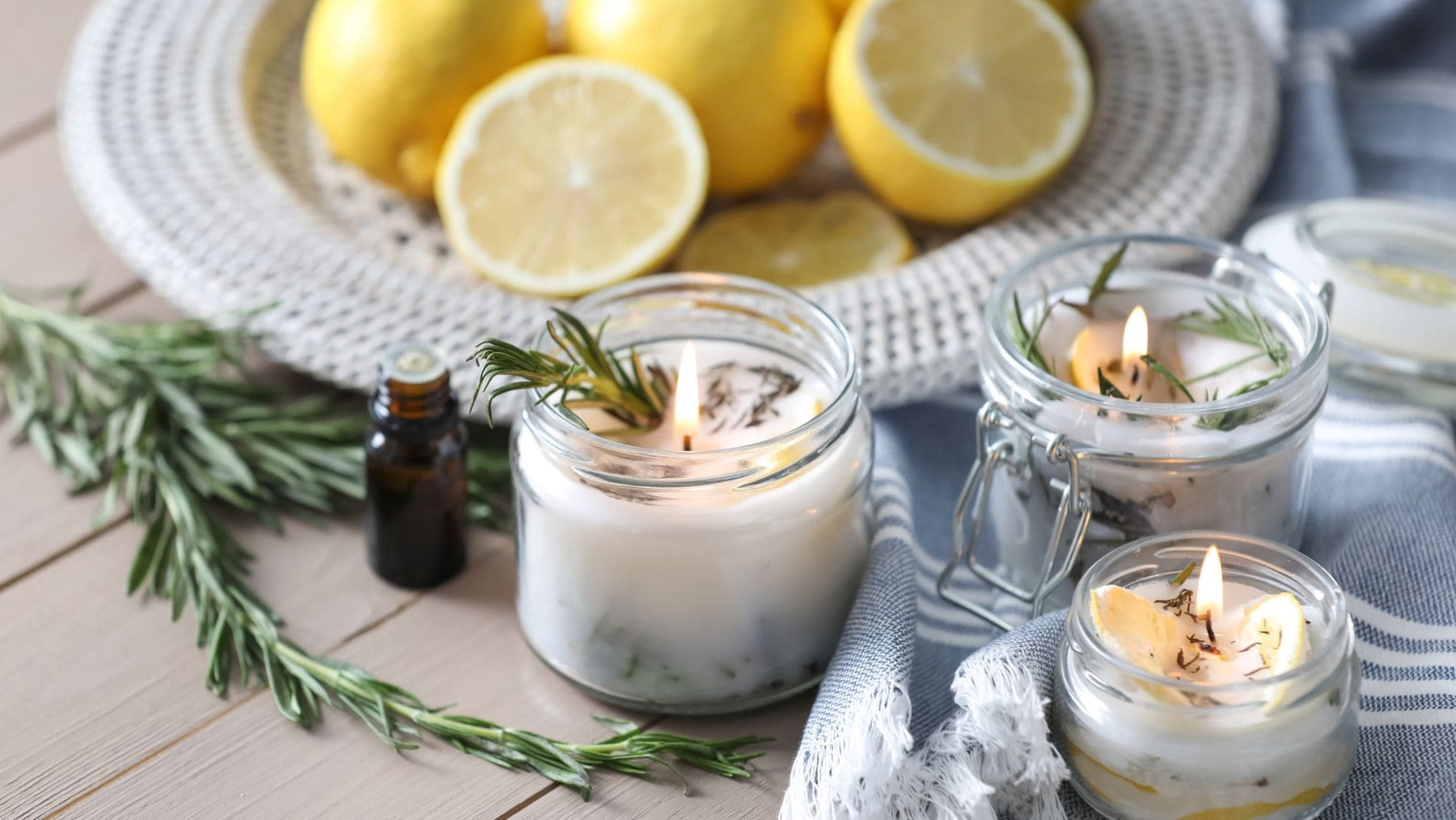 Natural mosquito repellent candles with lemon, rosemary, and essential oils on a summer outdoor hosting setup