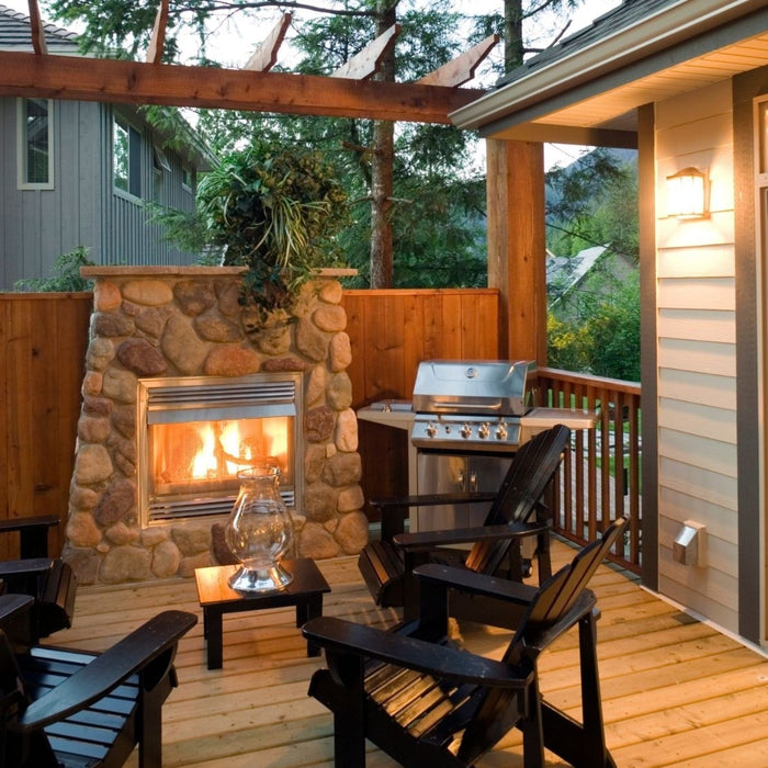 Cozy outdoor patio with a stone fireplace, Adirondack chairs, and a stainless steel grill, perfect for small gatherings or evening relaxation at a vacation rental.