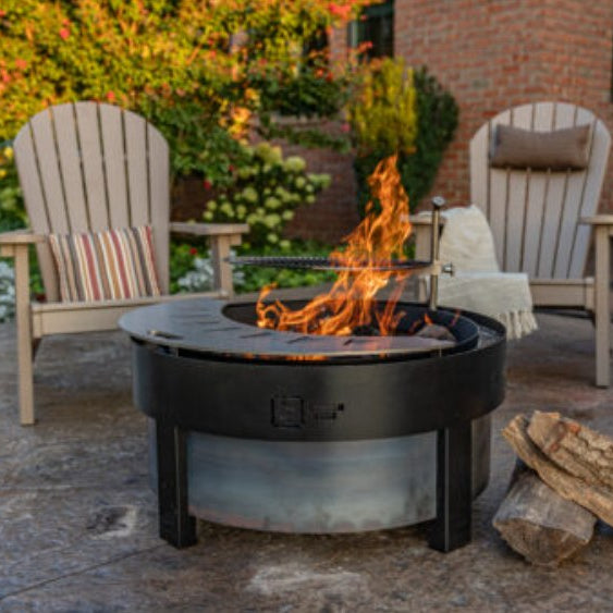Yard Craft The Forge smokeless fire pit burning on a stamped concrete patio with Adirondack chairs at golden hour