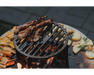 Arteflame Classic 20" Corten Steel Grill cooking meat skewers and potatoes on cast iron grate over open wood fire