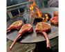 Arteflame Classic 40" Grill flat-top steel surface searing seasoned tomahawk ribeye steaks over open wood fire