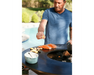Arteflame Classic 40" Grill with man squeezing lemon over salmon and potatoes on flat-top steel surface by pool