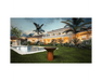 Arteflame Classic 40" Corten Steel Grill with Tall Round Base in luxury estate backyard with pool at sunset
