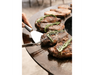 Arteflame Classic 40" Grill flat-top steel surface searing ribeye steaks with fresh rosemary and stainless steel spatula