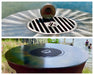 Crisbee Puck seasoning tin on Arteflame grill grate insert, showing before and after seasoned carbon steel cooktop surfaces