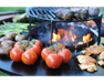 Arteflame Grill Grate Riser with steaks over open flame surrounded by tomatoes, mushrooms, asparagus, and chicken