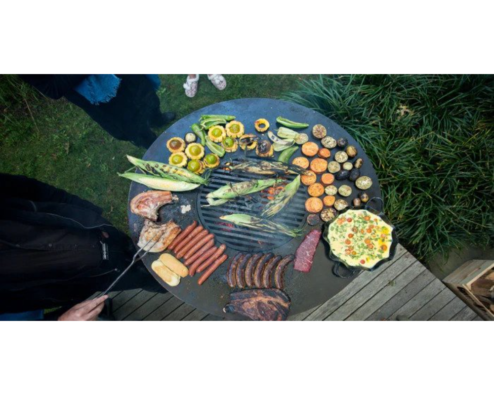Arteflame Grill Grate Insert overhead view with corn, sausages, steaks, and mixed vegetables on flat-top steel surface