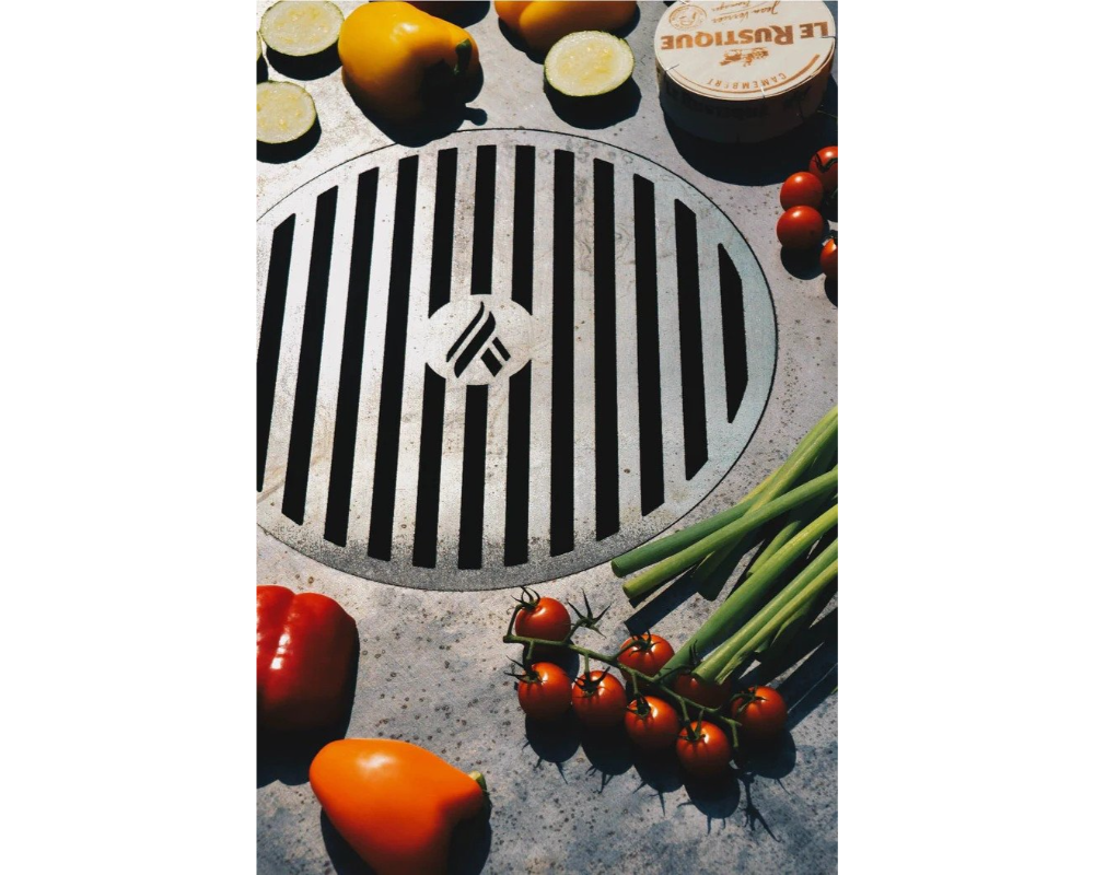 Arteflame Carbon Steel Center Grill Grate Insert surrounded by fresh tomatoes, peppers, zucchini, and green onions