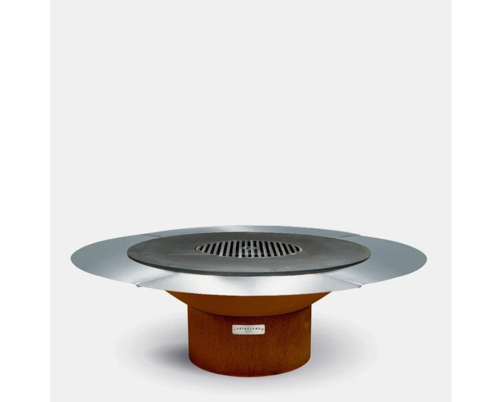 Arteflame round outdoor grill with stainless steel flat top, center grate, and corten steel base