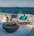Elementi Lunar Bowl round concrete fire pit with flames lit