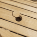 Kingsley Bate Hyannis teak dining table close-up of umbrella hole with teak plug on slatted tabletop
