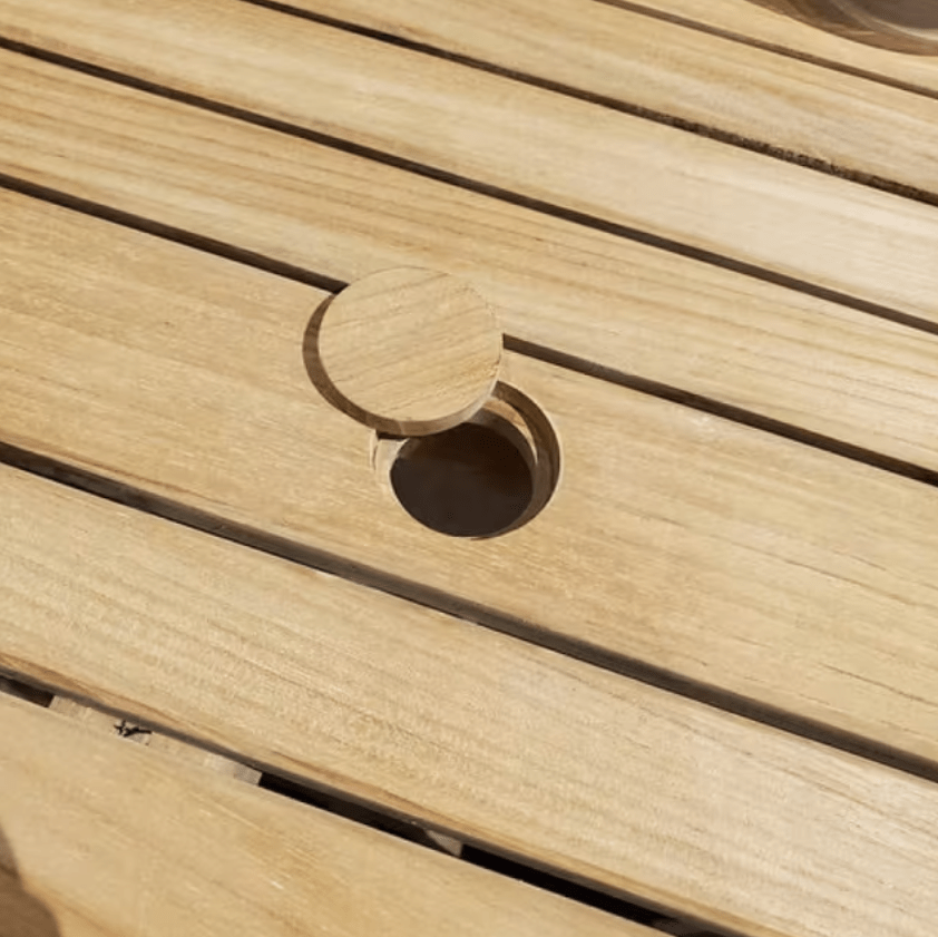 Kingsley Bate Hyannis teak dining table close-up of umbrella hole with teak plug on slatted tabletop
