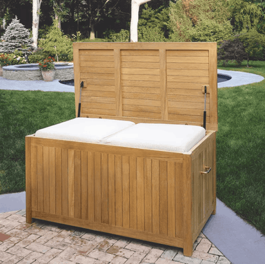 Kingsley Bate teak outdoor storage box shown open with cushions inside, slatted panels in garden setting
