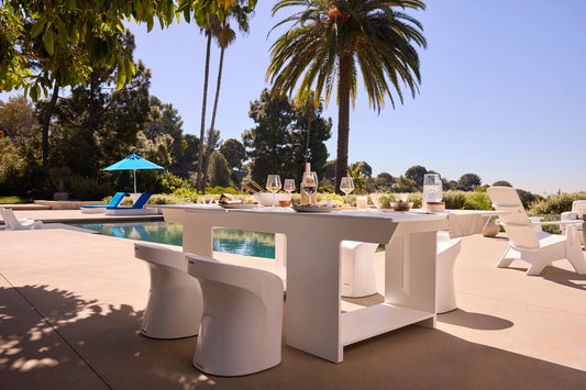Ledge Lounger table tennis table set for dining with Signature barstools on a palm-lined pool deck
