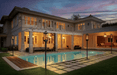 Multiple Travis Industries Tempest gas lanterns on in-ground posts lining luxury pool deck at dusk with large estate in background