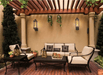 Travis Industries Tempest gas lanterns wall mounted on covered pergola patio with outdoor seating at dusk