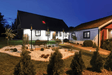 Travis Industries Tempest gas lanterns on in-ground posts flanking landscaped front yard of residential property at night