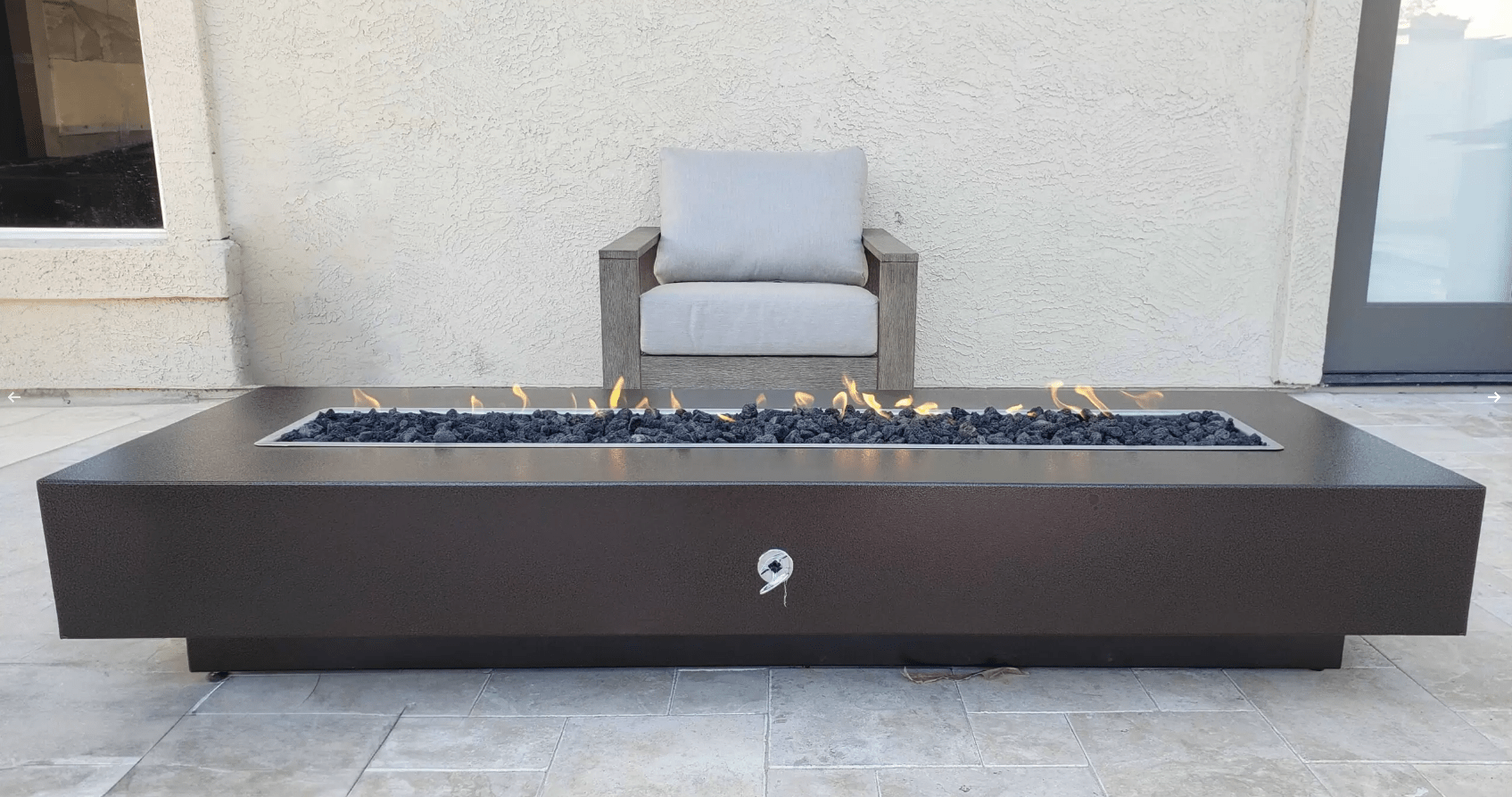 Modern outdoor fire pit table with flames in a patio setting.
