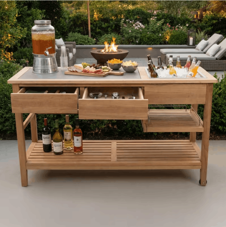 POVL Outdoor Calera teak buffet table styled for outdoor entertaining with food drinks and fire pit