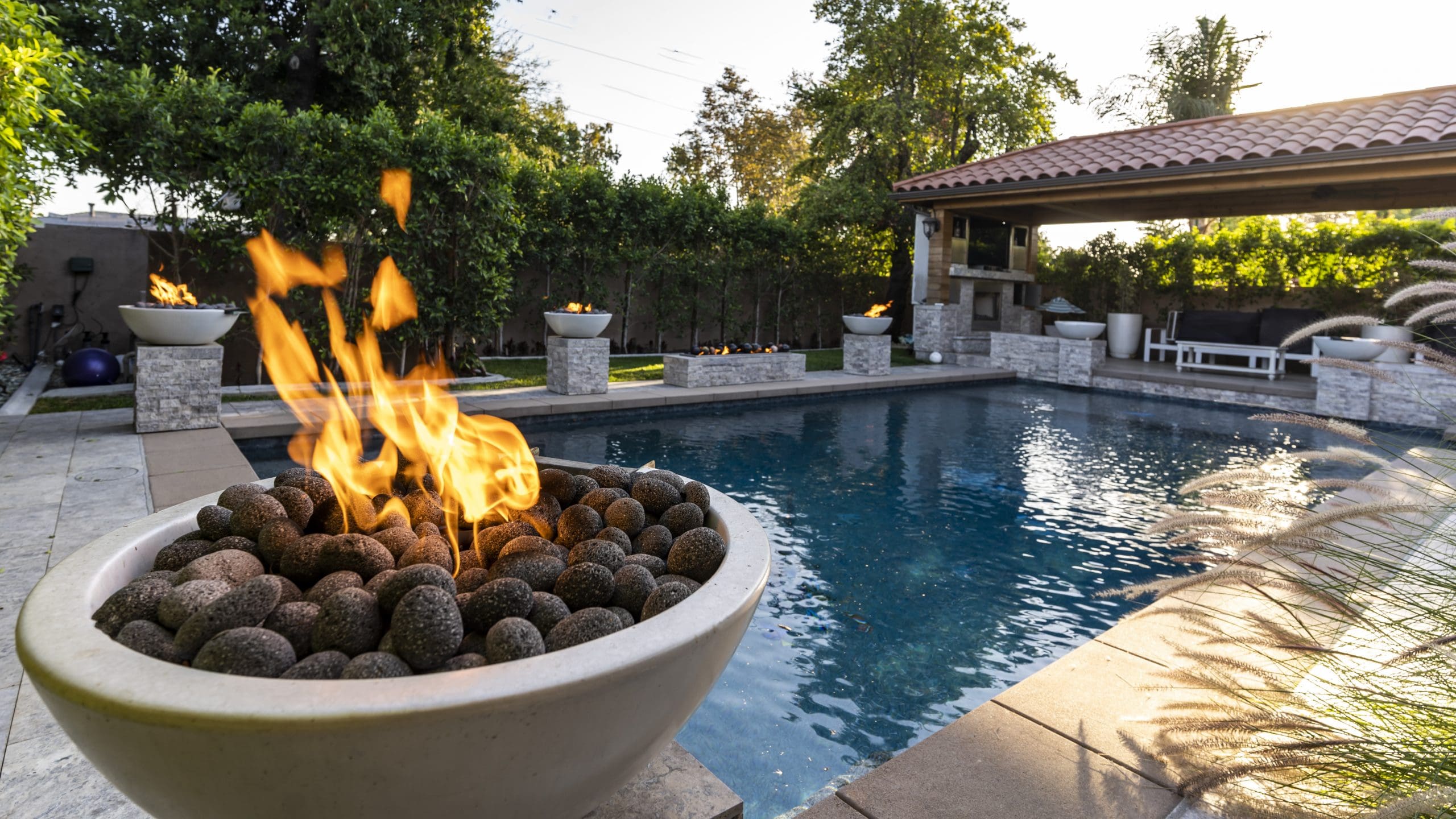 Fire pit with flames by a poolside in a backyard setting