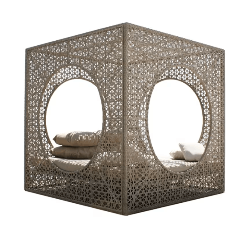 A modern outdoor cube daybed with intricate geometric laser-cut metal screens, featuring two large circular openings with cushions inside, shown on a white background.