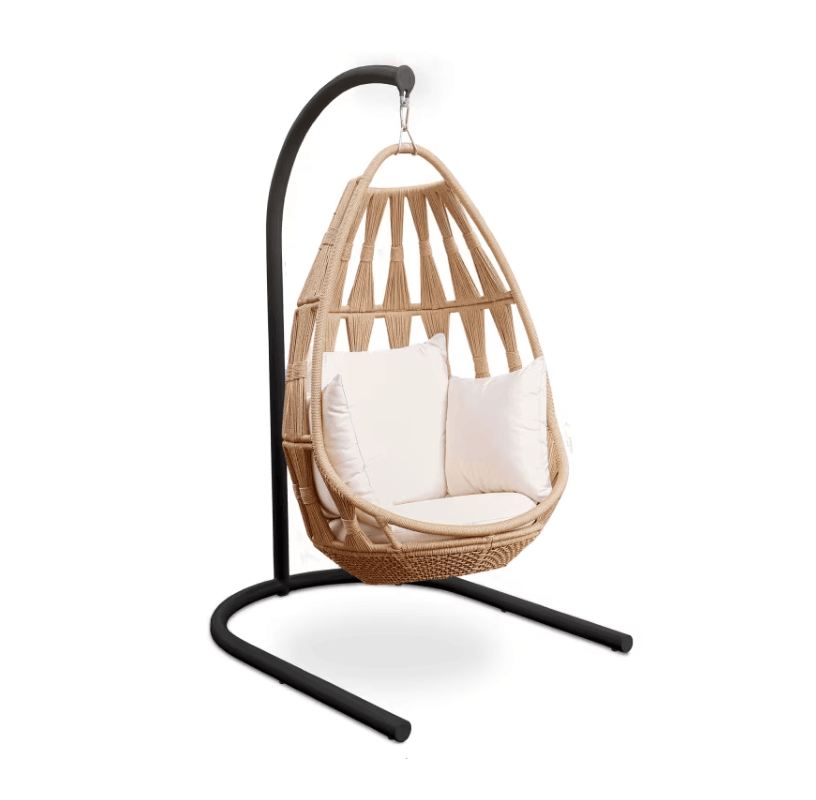 A teardrop-shaped woven rattan hanging chair with cream cushions, suspended from a black metal curved stand on a white background.