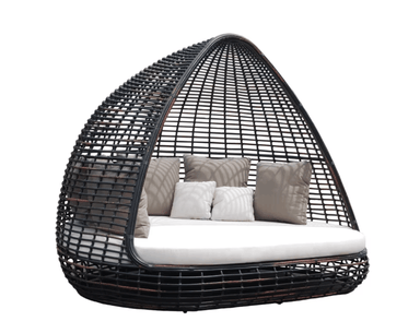 A dark woven wicker egg-shaped outdoor daybed with a white cushion and several beige and white throw pillows, shown against a plain white background.