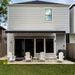 Black Awntech Destin motorized retractable awning with white hood extended over a patio with four white Adirondack chairs