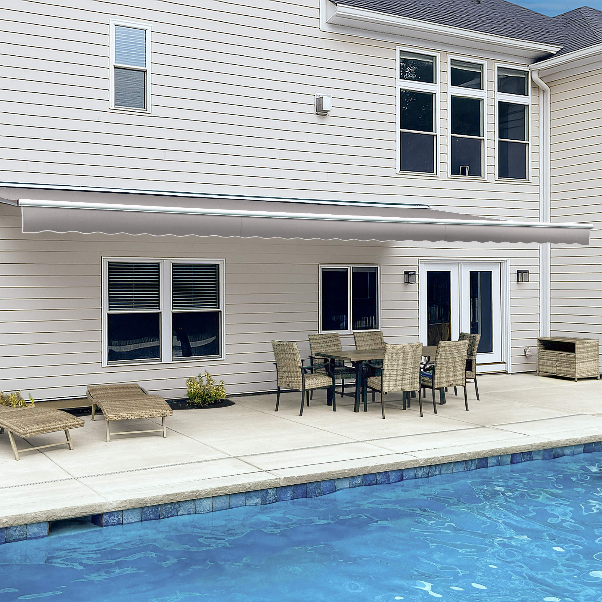 Awntech Destin motorized retractable awning in gray extended along a cream siding house over a poolside dining set