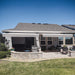 Two gray Awntech Key West full cassette retractable awnings mounted under the eave of a one story house over a paver patio