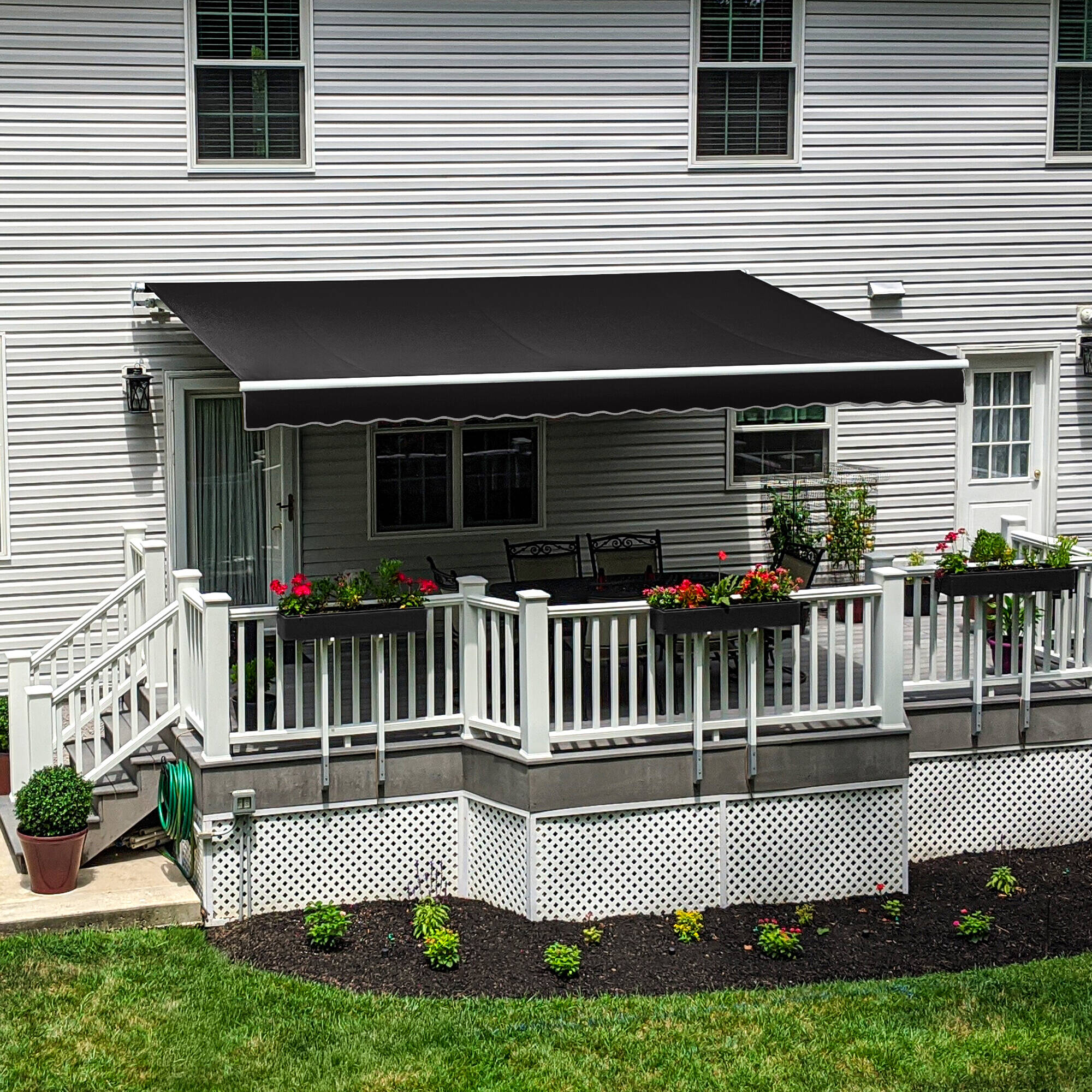 Black Awntech Maui motorized retractable awning extended over a white railed deck with a dining table and flower boxes