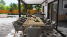 Black Equinox louvered pergola with double-wall blades attached to a home, covering an outdoor dining table set for a meal