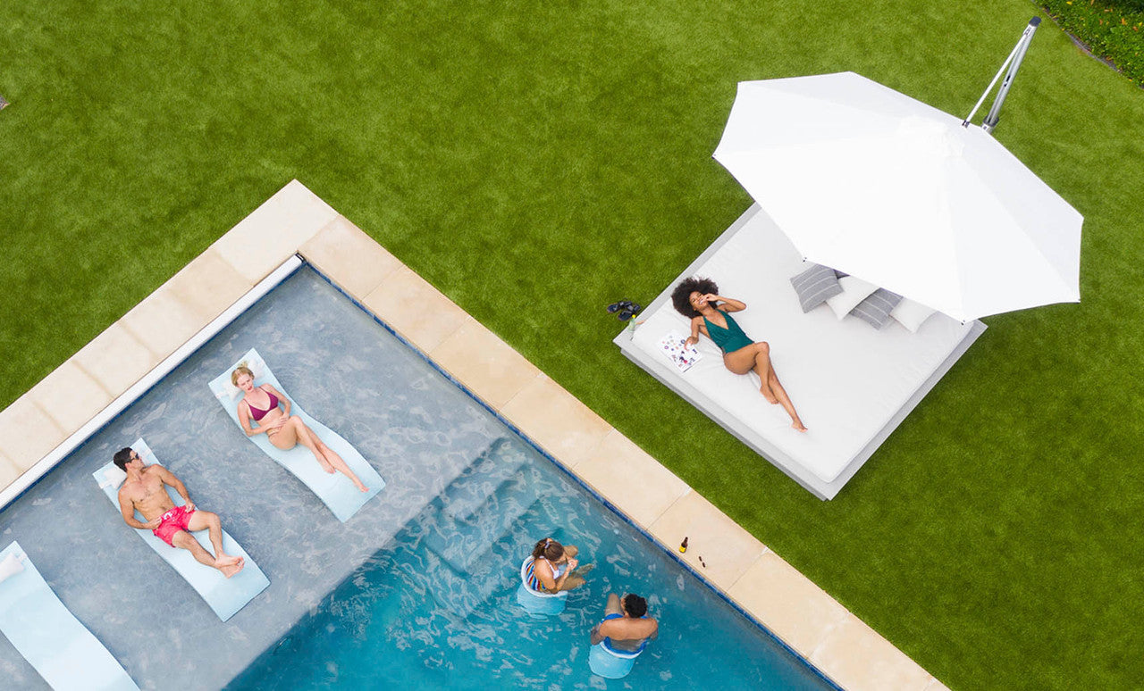 Ledge Lounger Ultra cantilever umbrella shading a pool ledge and loungers