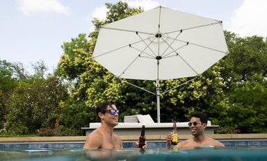 Guests relaxing in a pool under a Ledge Lounger Ultra cantilever umbrella