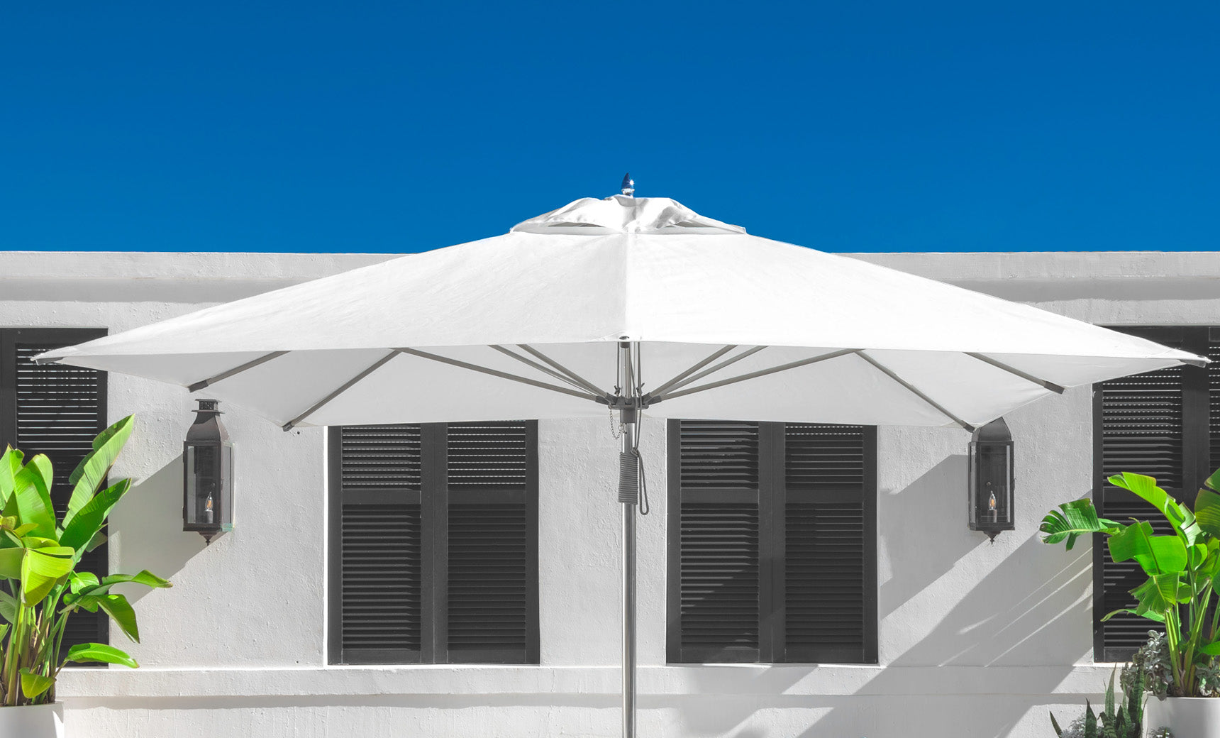 Ledge Lounger Essential pool umbrella shown in an outdoor setting, lifestyle photo 5 of 7