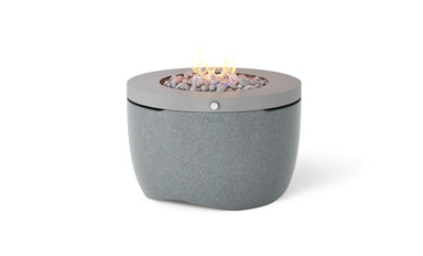 Ledge Lounger Halo Firepit in Twilight gray with a steel top and a small flame over gray rocks, on a white background