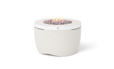Ledge Lounger Halo Firepit in Moonrise, a light white finish, lit with a small flame over rocks